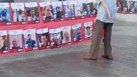Thumbnail for An elderly Israeli man blows kisses to photos of the men, women and children being held hostage by Hamas in Gaza.